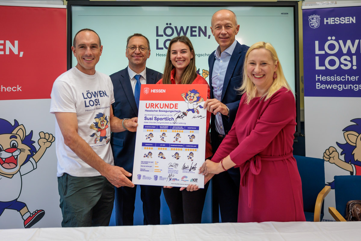 Gruppenfoto bei der Urkundenübergabe zum Hessischen Bewegungscheck ‚Löwen, los!‘. Fünf Beteiligte präsentieren die Urkunde ‚Susi Sportlich‘ zur Förderung von Bewegung und Sport bei Kindern in Hessen.